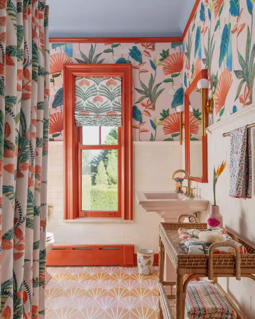 Colorful bathroom with tropical wallpaper, patterned curtain, coral trim, and geometric floor tile