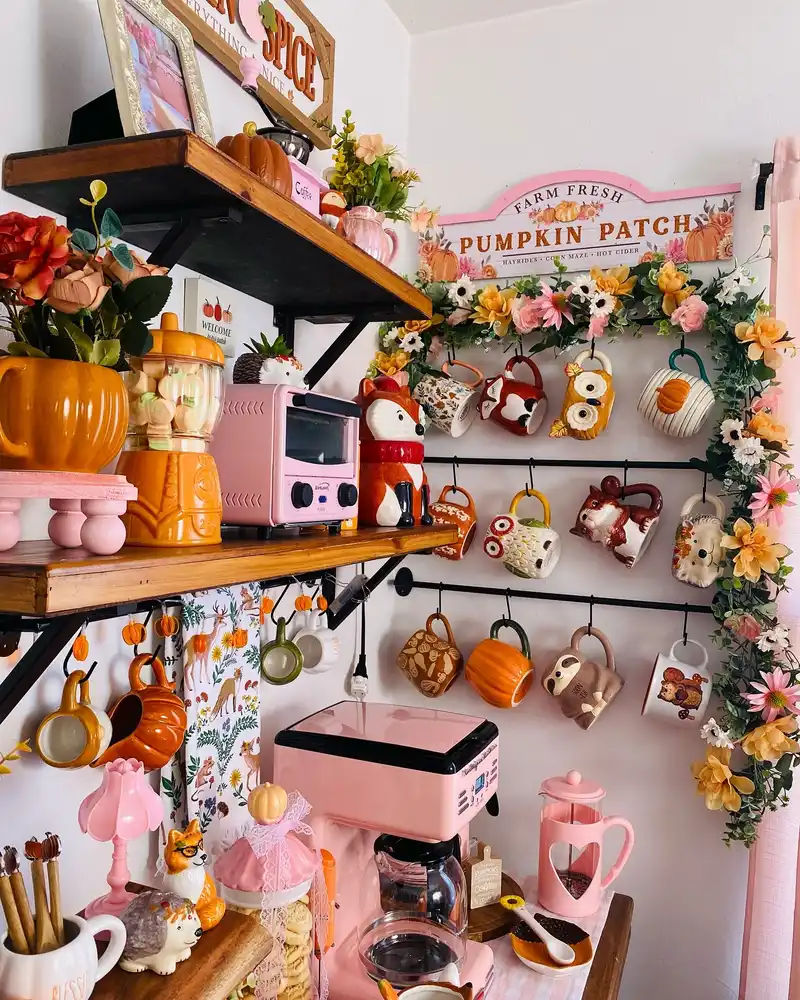 Pink fall coffee station with a pink coffee maker, fox mugs, pumpkins, orange accents, and floral garland