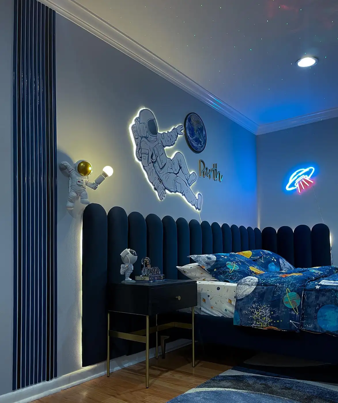 Gray bedroom with glowing astronaut wall decor, space bedding, neon planet light, and starry ceiling lights