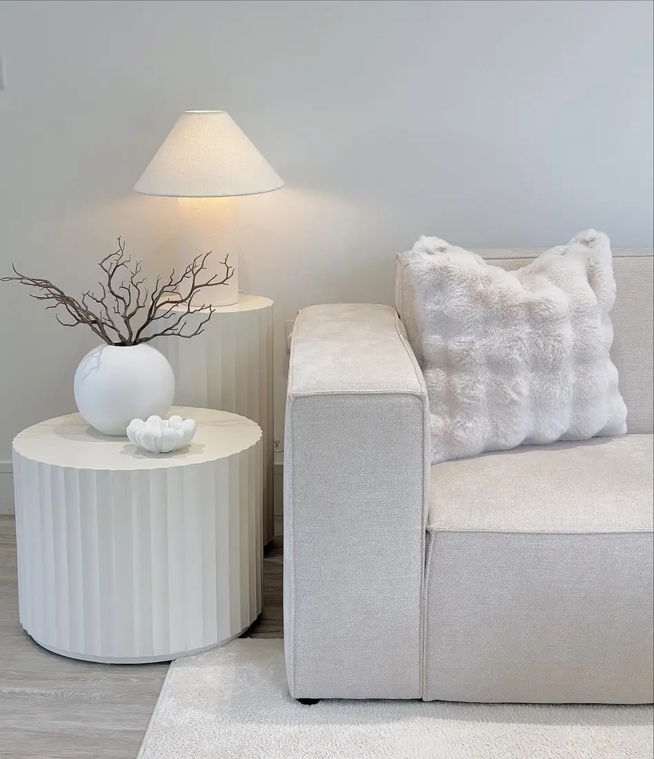 Minimal fall table decor with bare branches in a round white vase and one small pale pumpkin