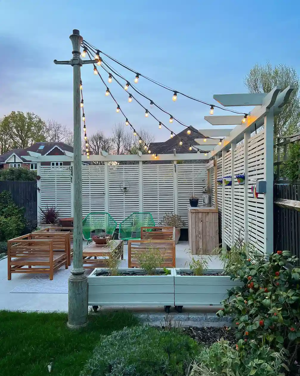 Outdoor string lights hanging above a pergola with a patio dining area