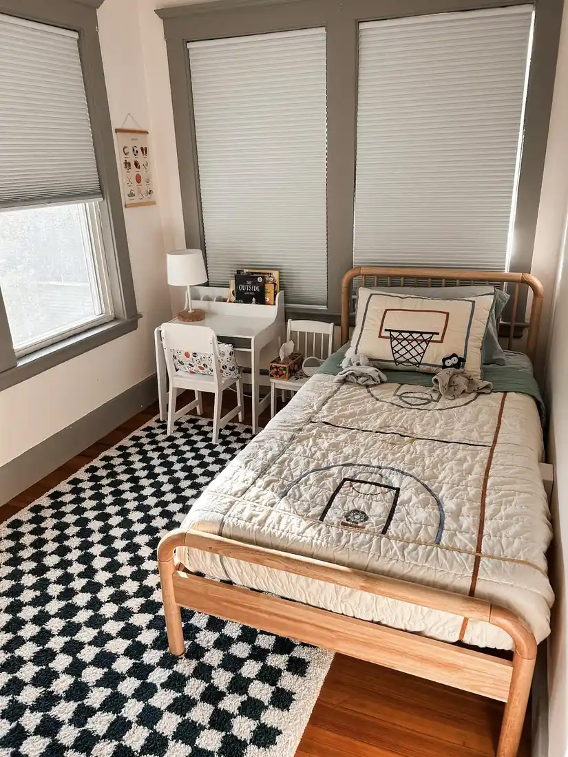 Small kids bedroom with single bed by corner windows, side table, and black and white rug