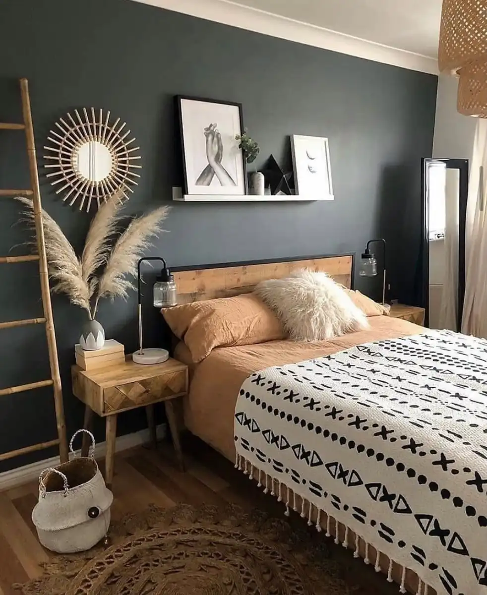 Charcoal bedroom with a rustic wood headboard, cream bedding, woven pendant light, warm wood furniture, and pampas grass