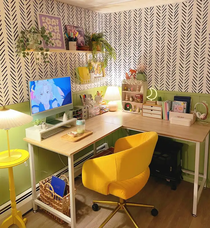 L-shaped dorm desk with computer monitor, yellow chair, patterned wall, and green accents