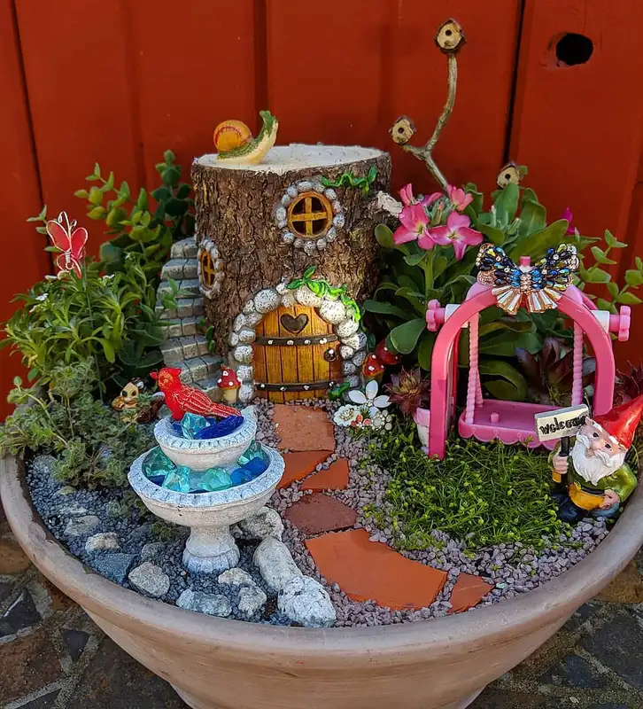 Colorful fairy garden with miniature houses, flowers, mushrooms, and bright pink, blue, and red accents