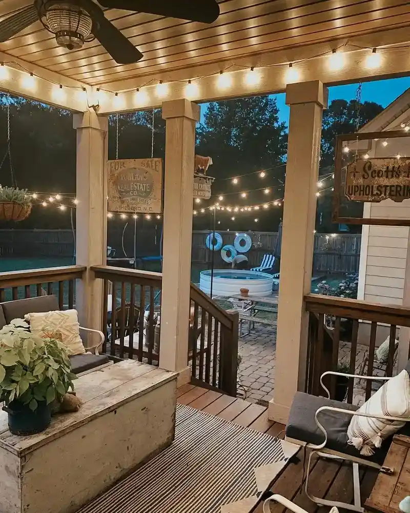 Screened porch with wood flooring and ceiling, string lights, comfortable seating, and potted plants.