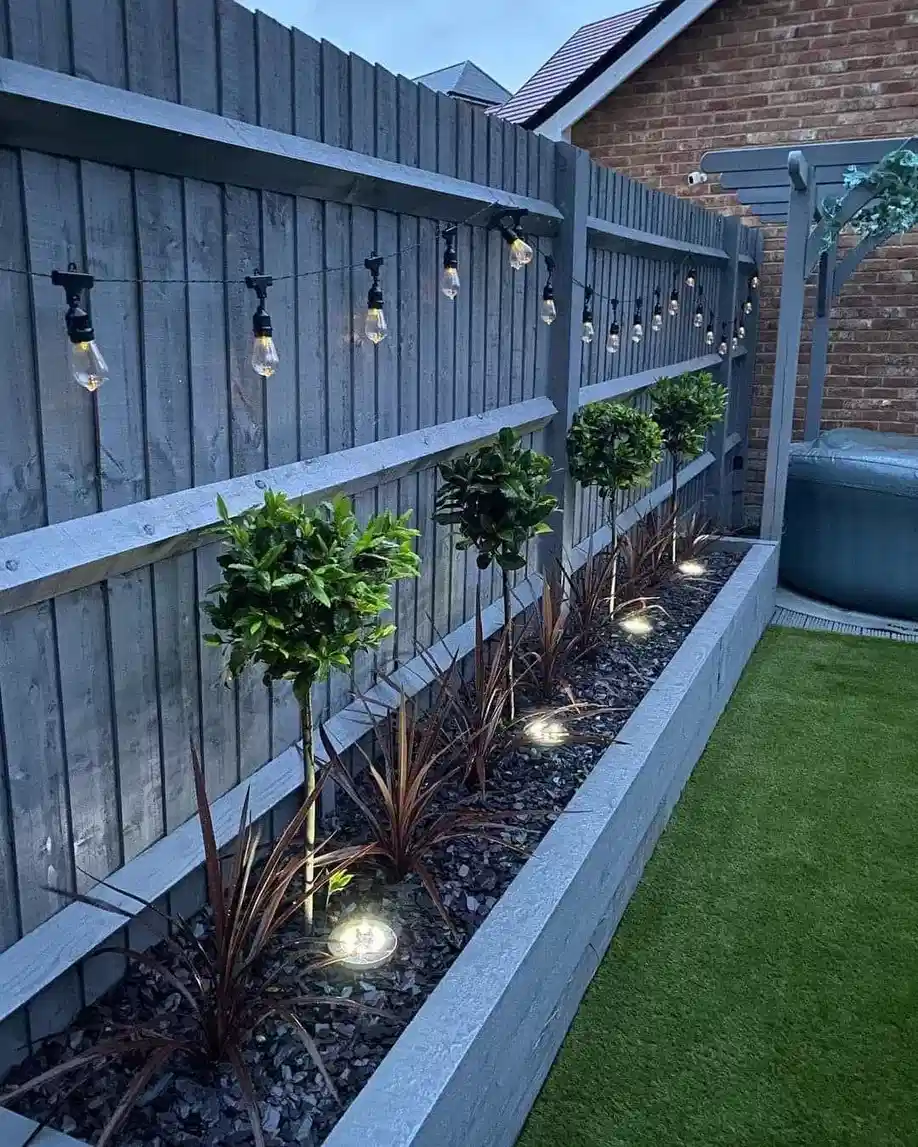 Outdoor string lights illuminating a narrow side yard with a pathway and planted border