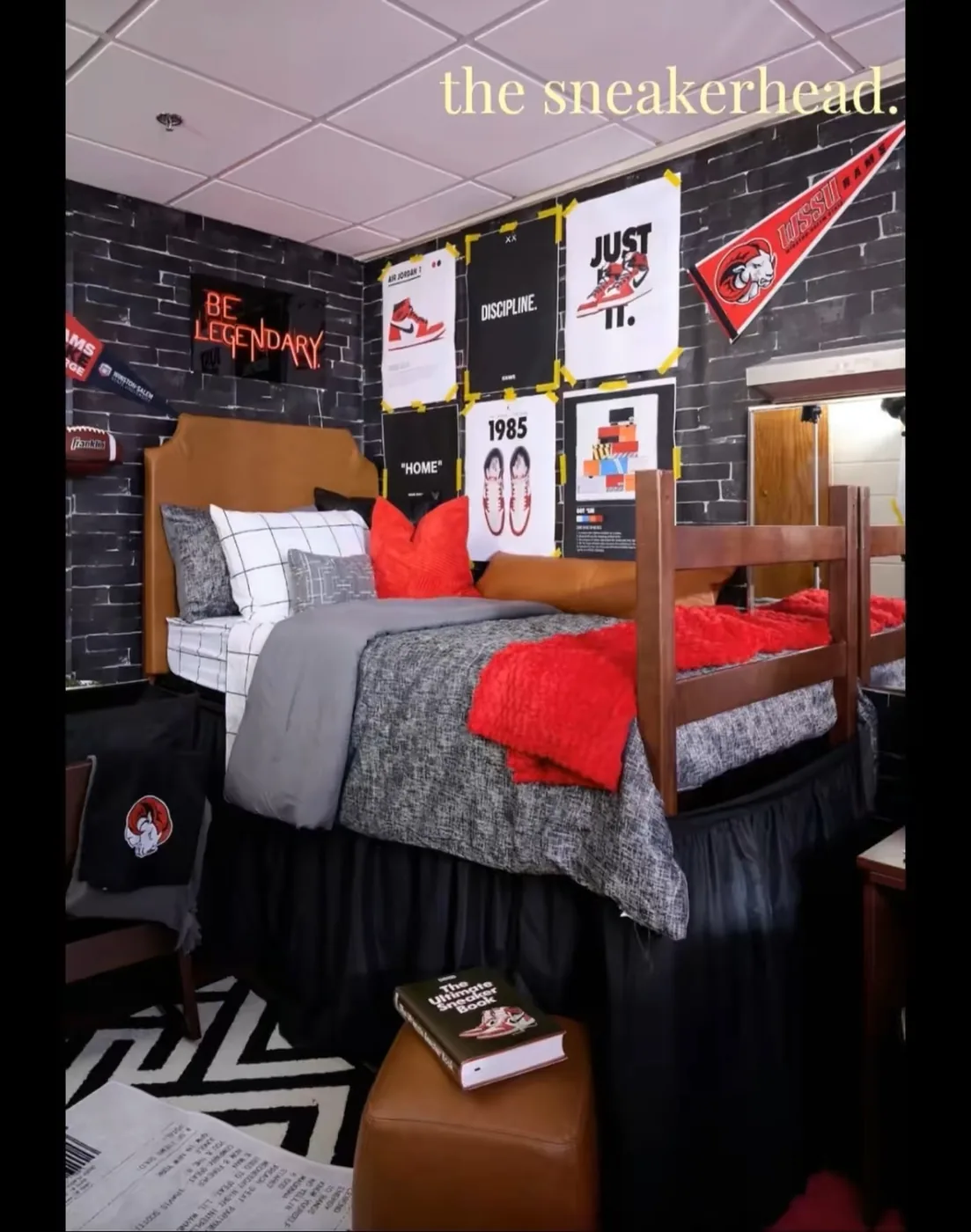 Sneaker-themed dorm room with dark walls, gray bedding, red accents, sports pennants, and shoe artwork