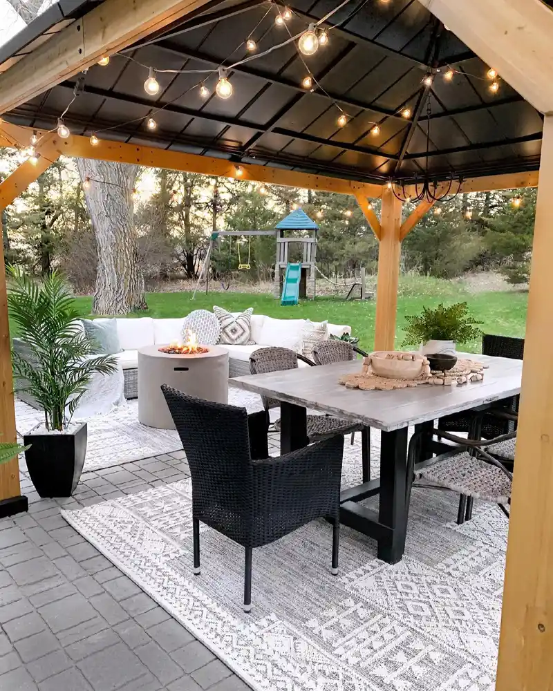 Pale patterned outdoor rug beneath a dining table and chairs on a covered patio.
