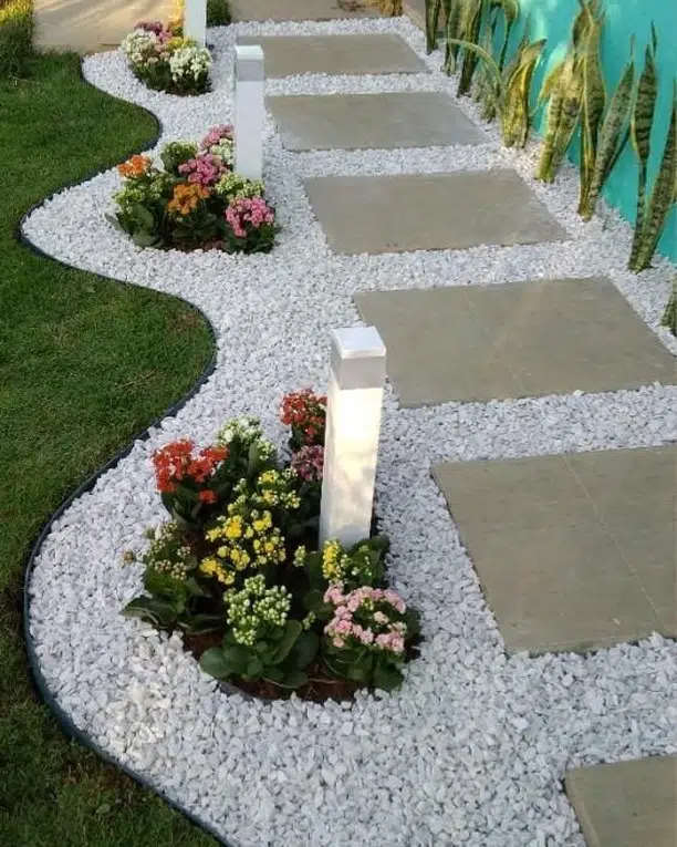 Large rectangular stepping stones set in pale gravel with small plants growing between the slabs.