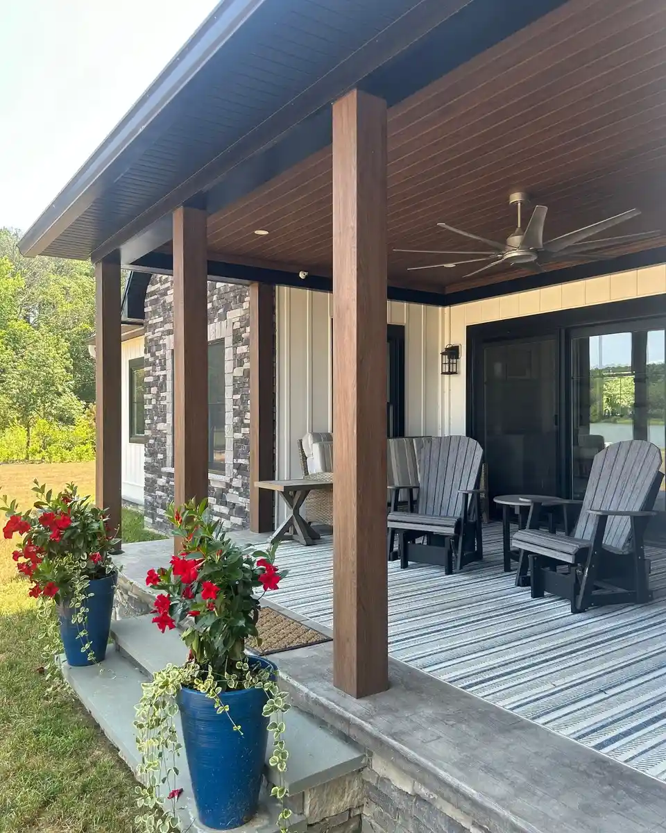 Long covered porch with dark wood posts, white railing, blue planters, and outdoor seating