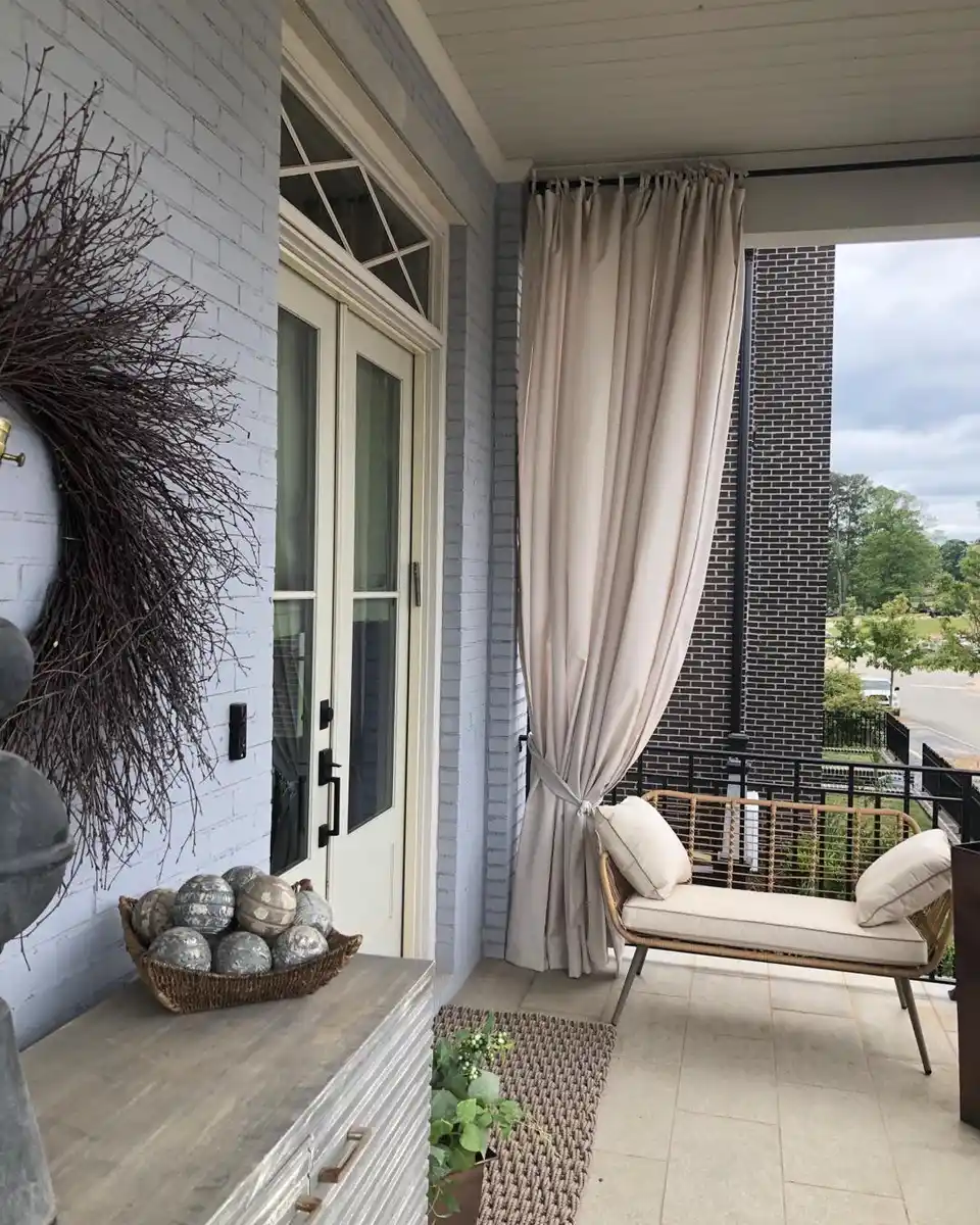 Covered porch with outdoor seating, long curtains, stone wall, and open garden view