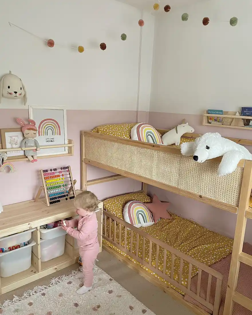 Small pink kids bedroom with wooden bunk bed and low toy and book storage