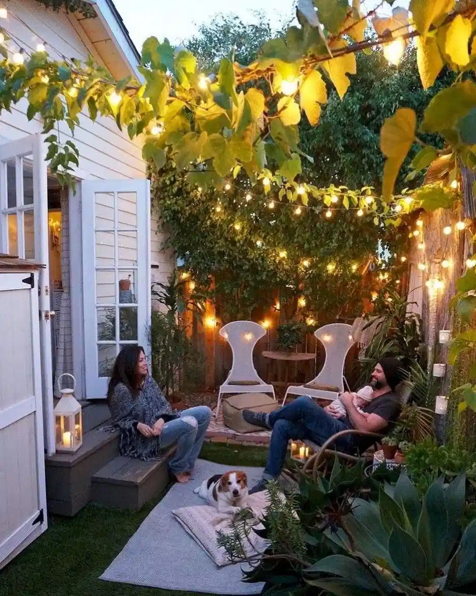 Outdoor string lights hanging above a garden dining table surrounded by plants