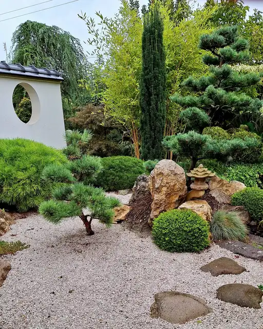 Zen garden with white gravel, dark rocks, and neatly trimmed evergreen shrubs