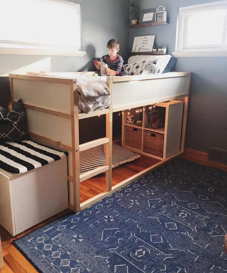 Kids loft bedroom with raised bed, cube storage, baskets, books, and floor seating underneath