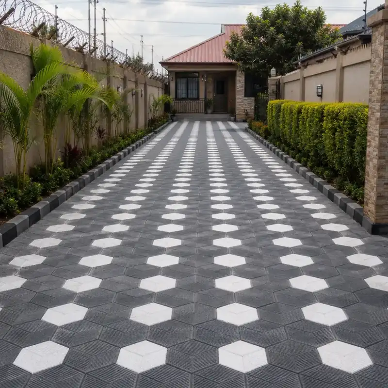 Dark driveway featuring a bold pattern of pale hexagonal pavers bordered by tall hedges