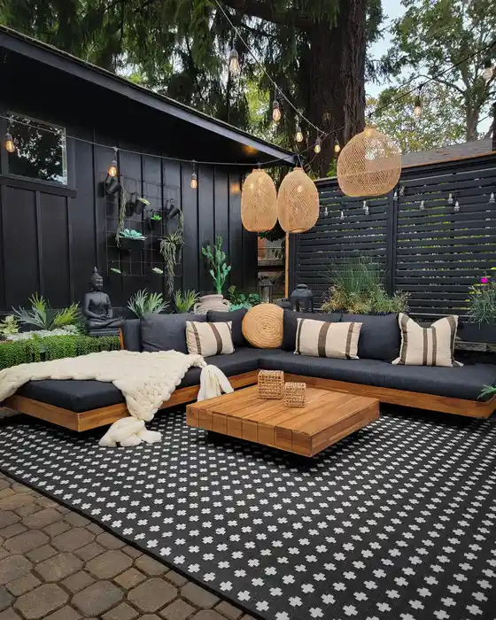 Black and white dotted outdoor rug beneath dark patio furniture with a warm wood coffee table.
