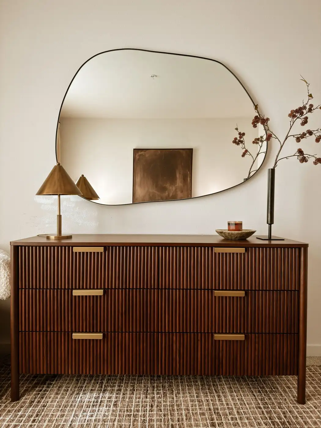 Ribbed wood dresser with brass hardware, slim lamps, tall branch, and minimal decorative objects