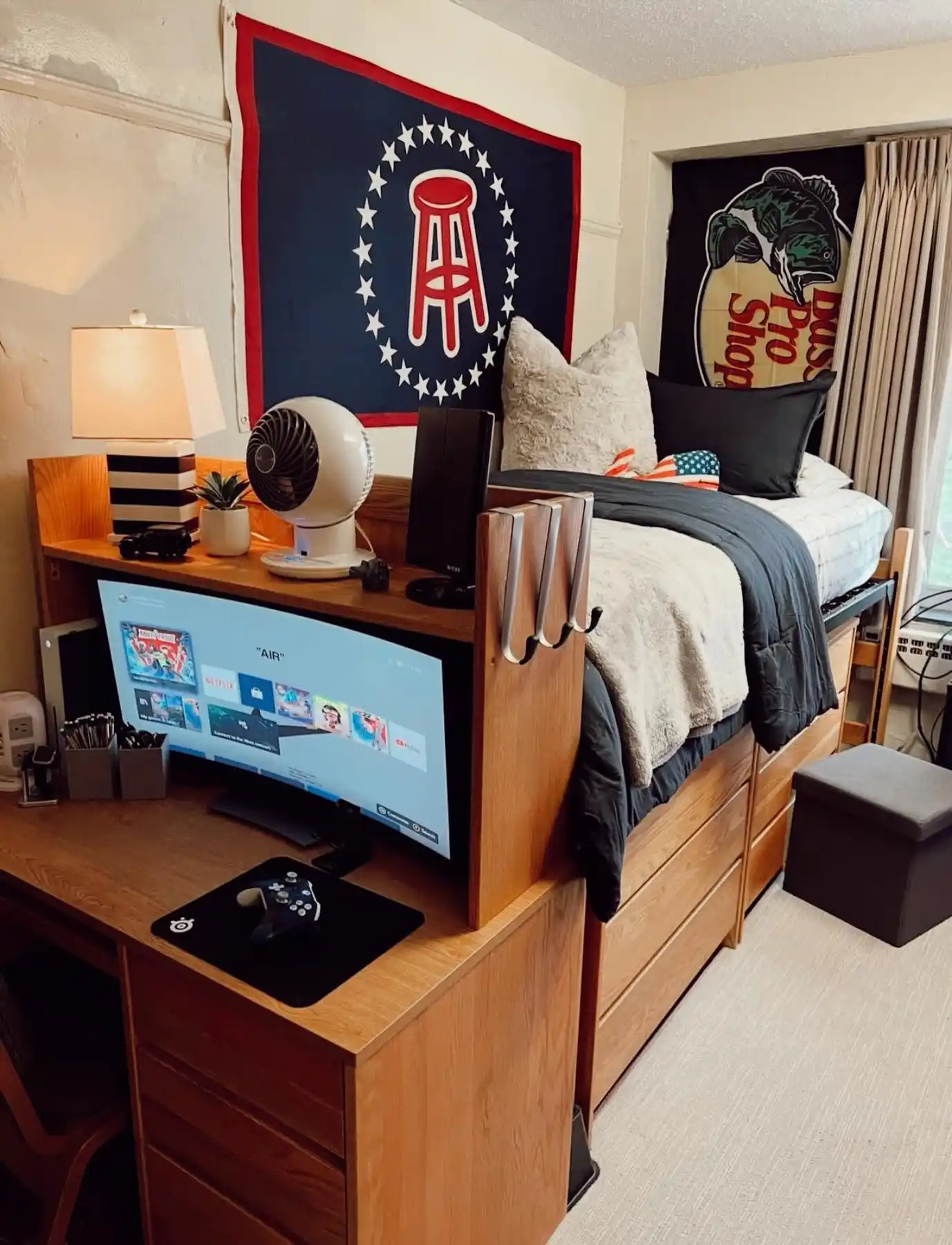 Dorm desk tucked beneath a raised bed with computer monitor and compact study area