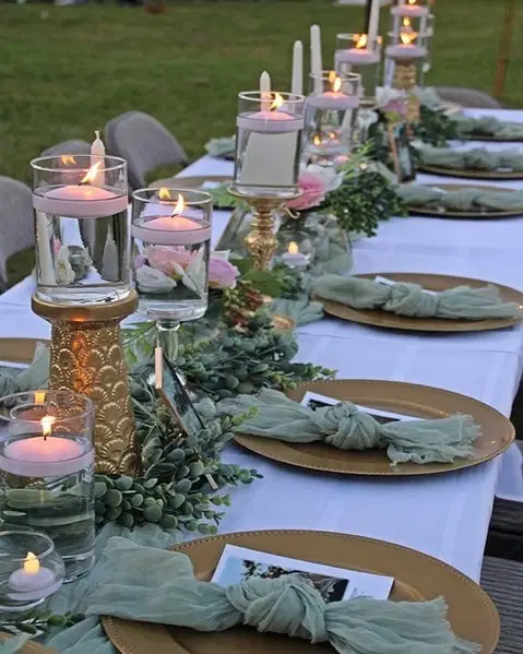 Outdoor garden dining table decorated with candles, greenery, and soft evening lighting