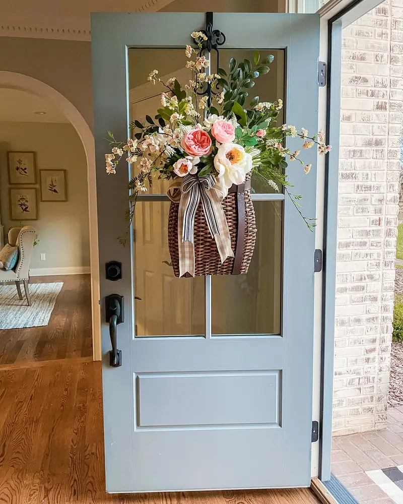 Light blue front door with a hanging basket of pink and white flowers