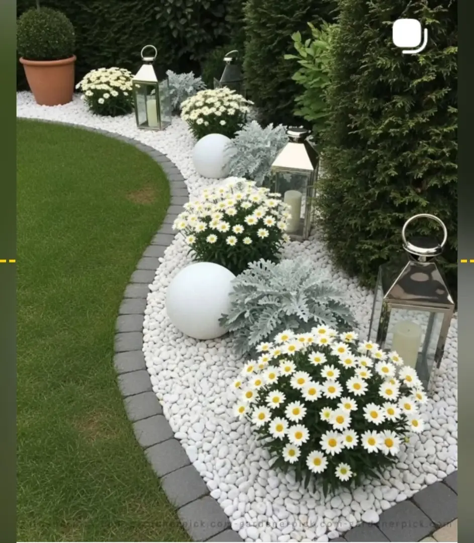 Curved front flower bed filled with white flowers, pale foliage, and light-colored gravel