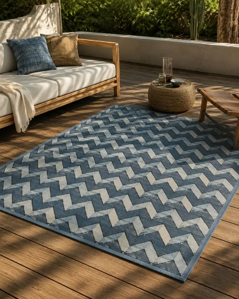 Blue zigzag outdoor rug on a wooden deck beneath neutral outdoor seating.