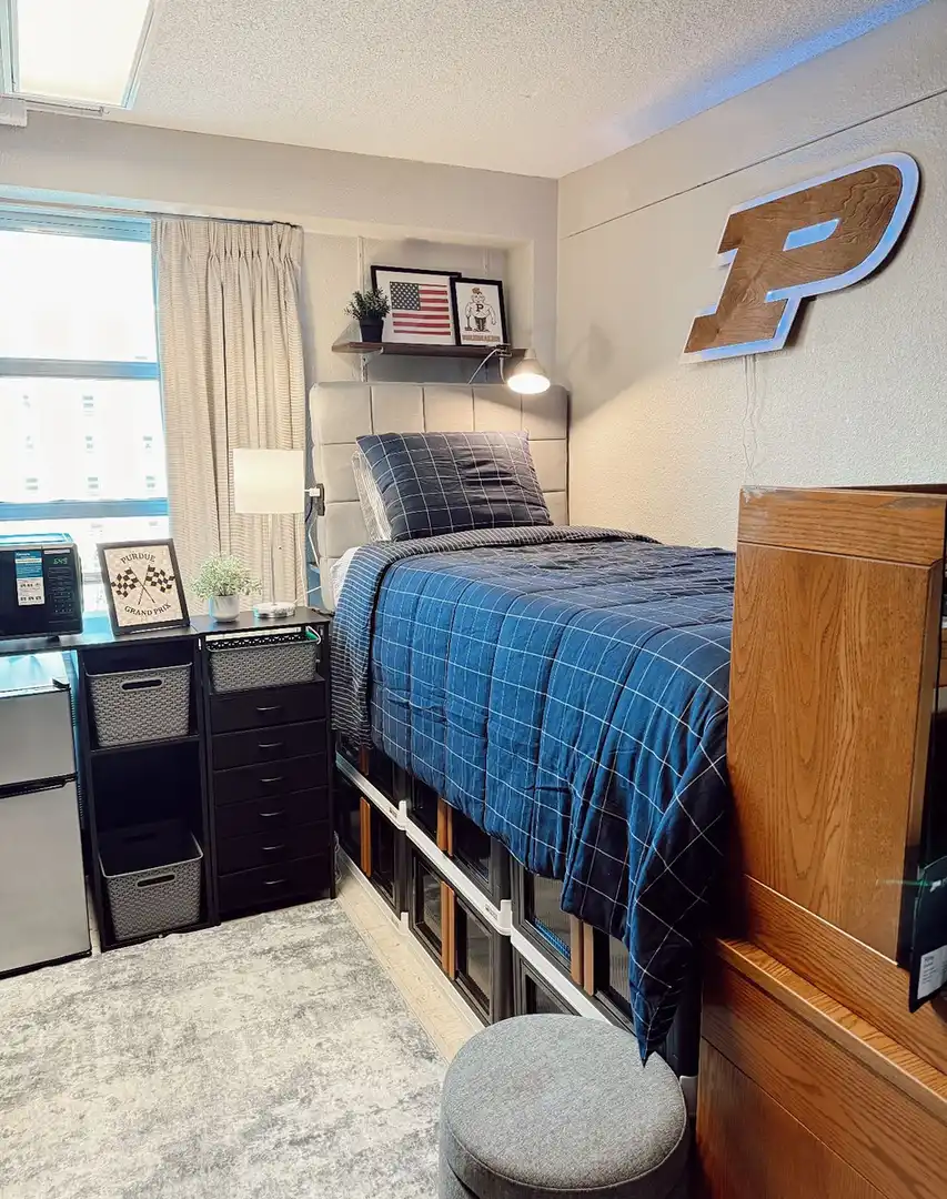Raised dorm bed with storage bins, bags, and other items organized underneath