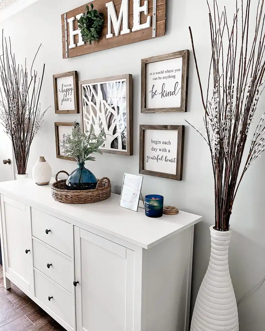 Dresser with tall floor branches on both sides, layered wall art, tray, candle, and small decorative pieces