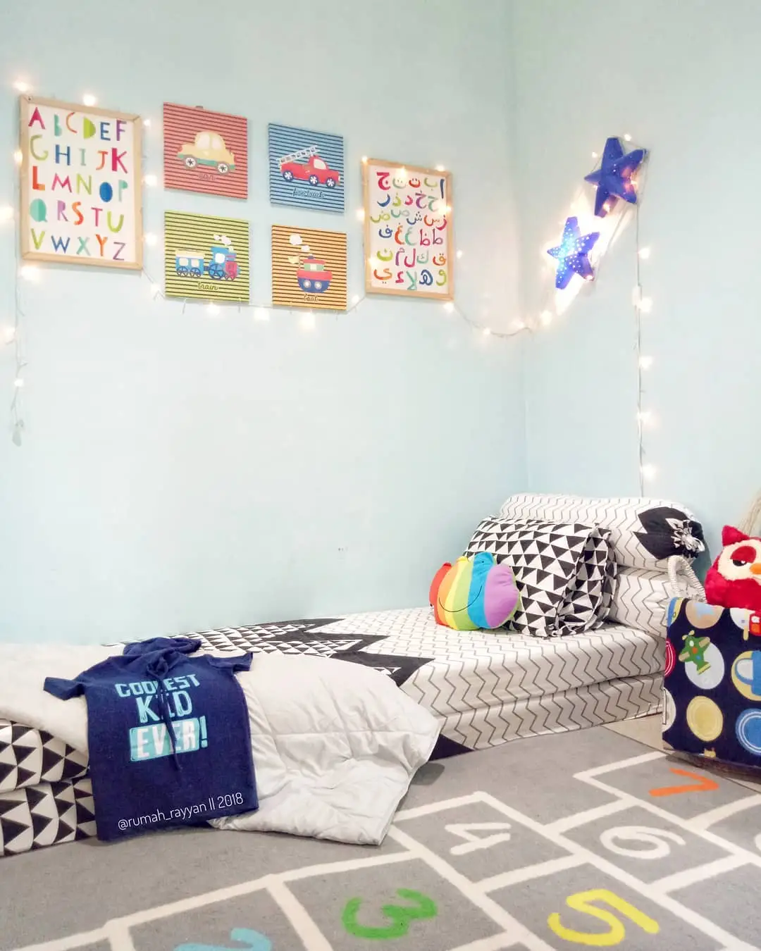 Small kids bedroom with colorful hopscotch rug, wall art and string lights