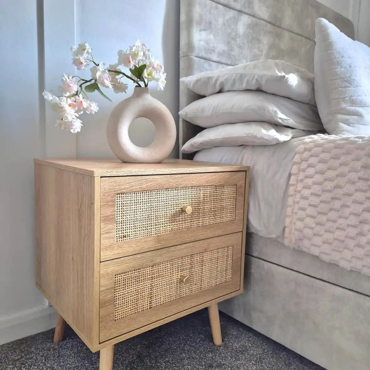 Cane-front nightstand with single rounded vase and tall flowering branches