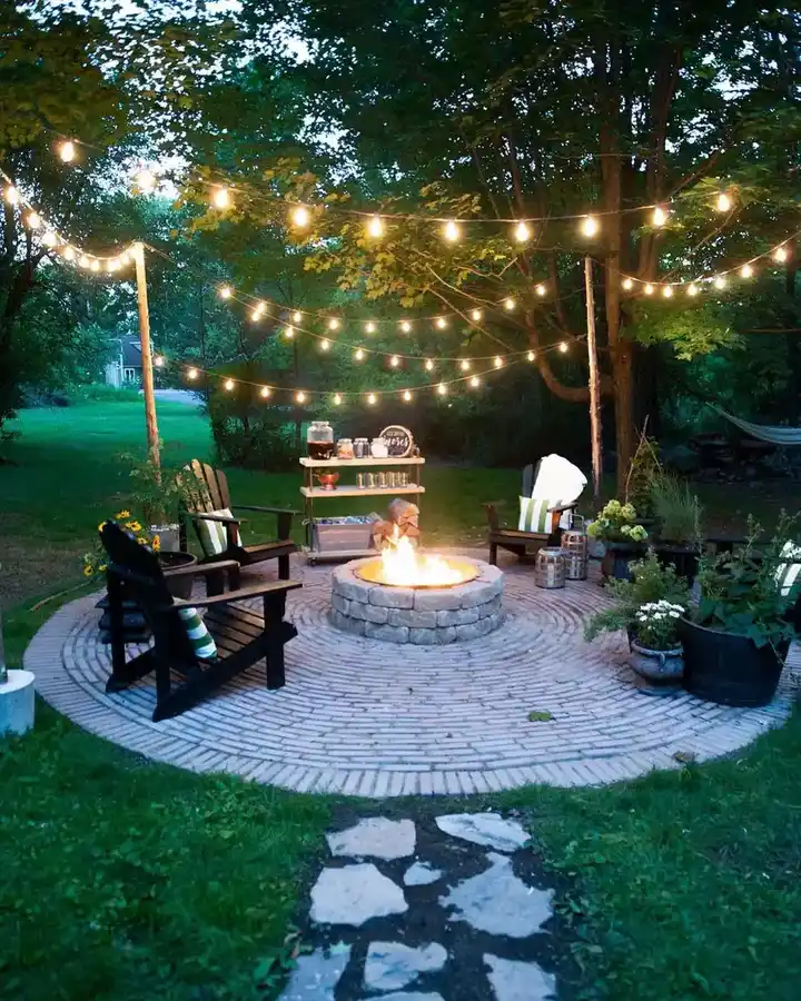 Circular backyard fire pit gathering area with outdoor chairs, string lights, and a stepping-stone path