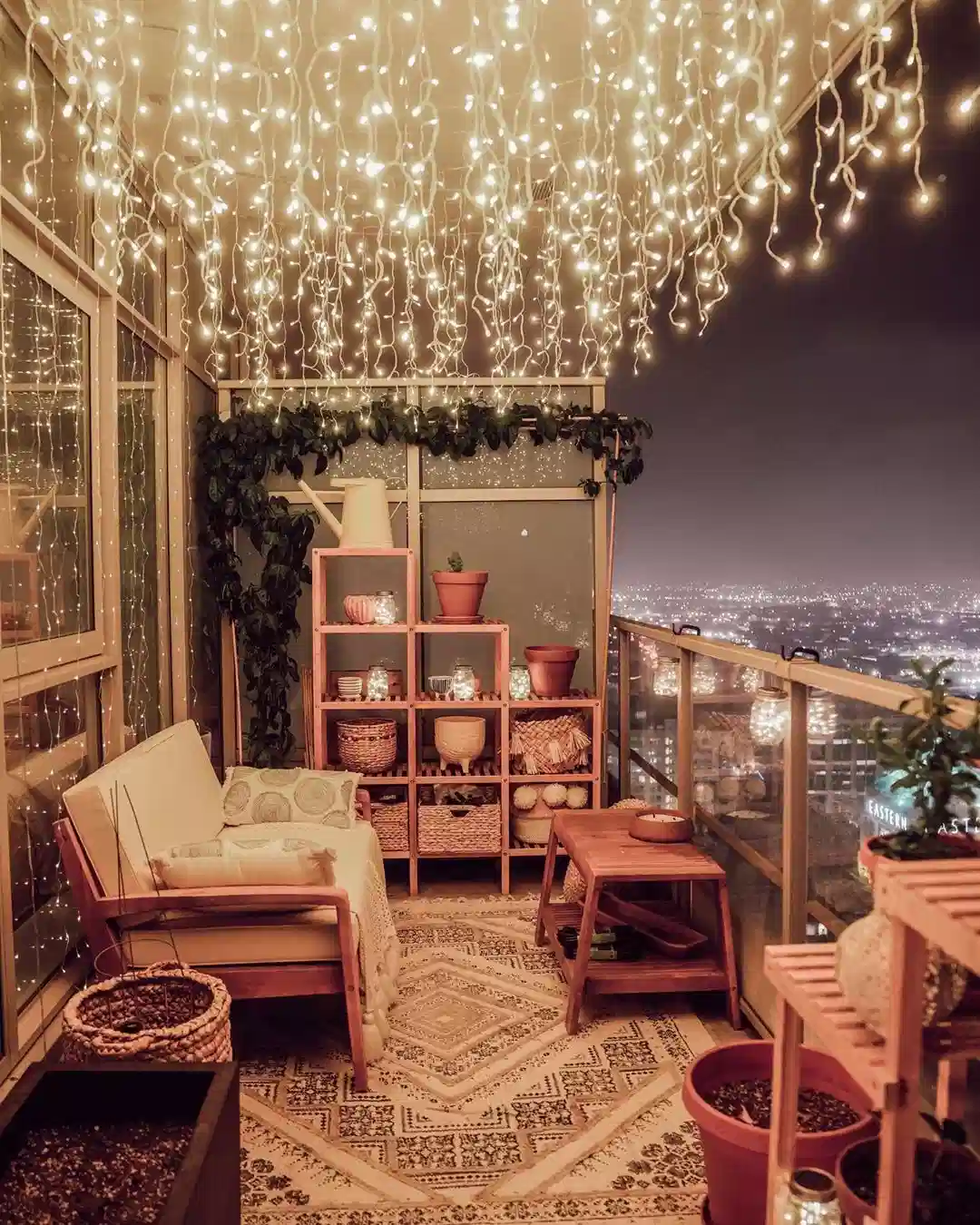 Dense canopy of warm fairy lights covering a small balcony ceiling above seating