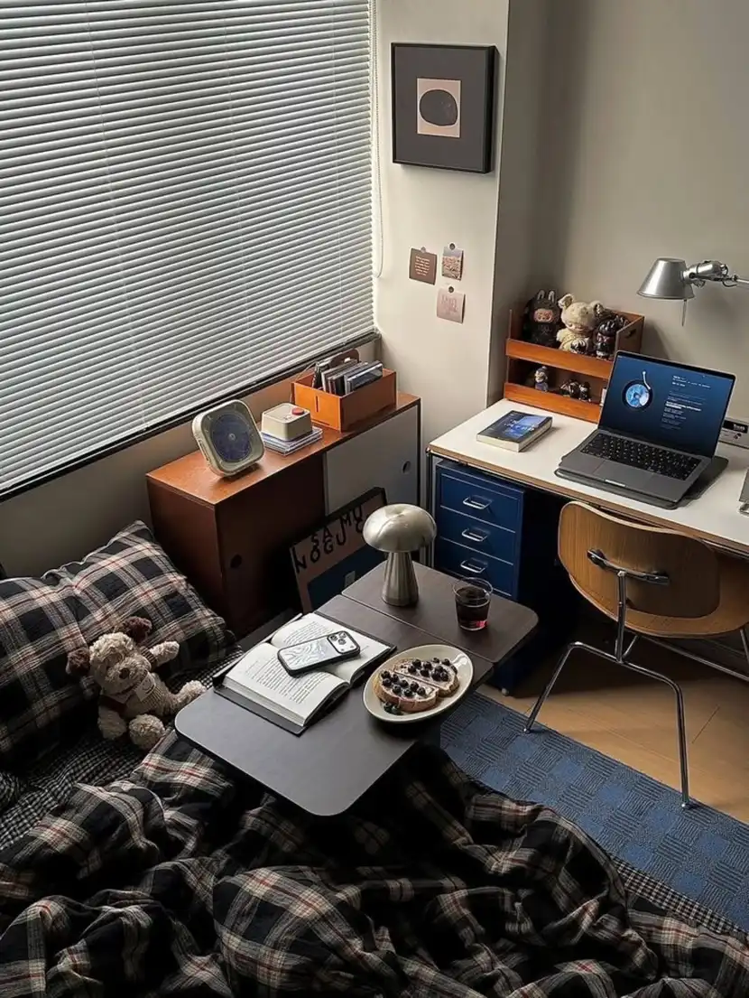 Narrow dorm desk beside a bed with blue drawers and compact storage