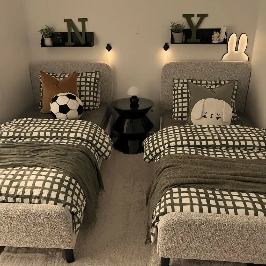 Small shared kids bedroom with two matching beds, central nightstand, and personalized wall initials