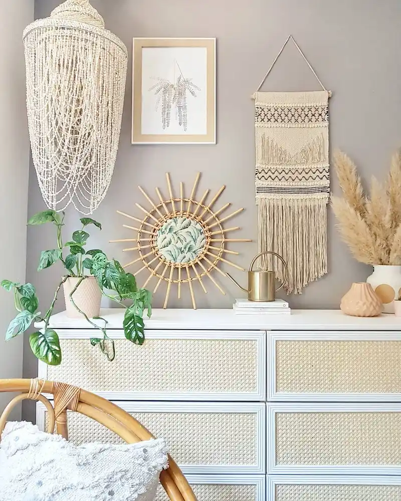 Boho dresser with sunburst mirror, woven wall decor, plants, dried grasses, and natural textures