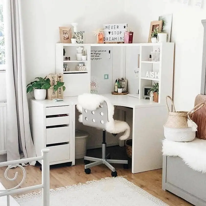 White dorm desk with drawers, upper shelves, woven baskets, plants, and fluffy chair