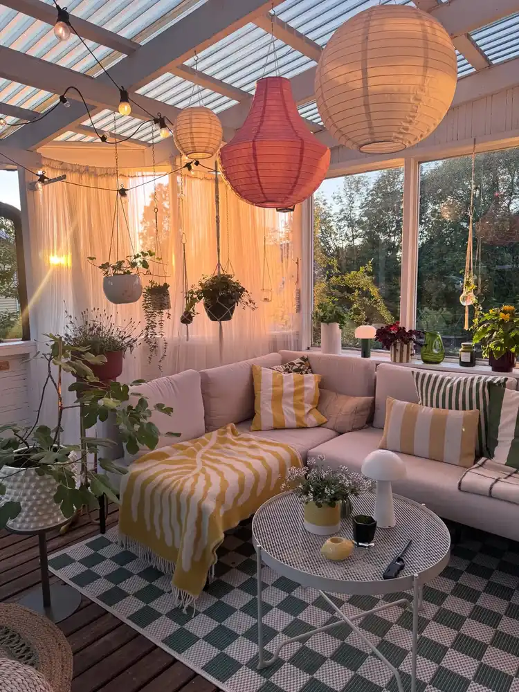 Pink and cream striped outdoor rug on a covered patio with hanging lanterns and warm lighting.