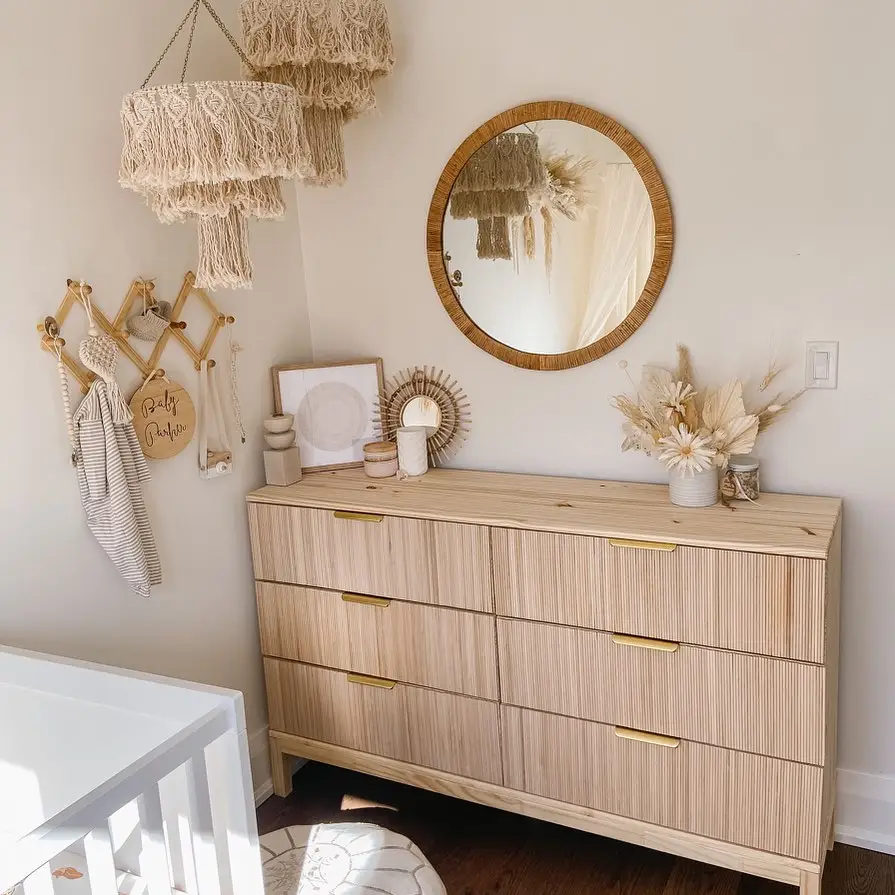 Pale wood dresser with woven mirror, fringed wall hanging, peg rack, dried flowers, and neutral pottery