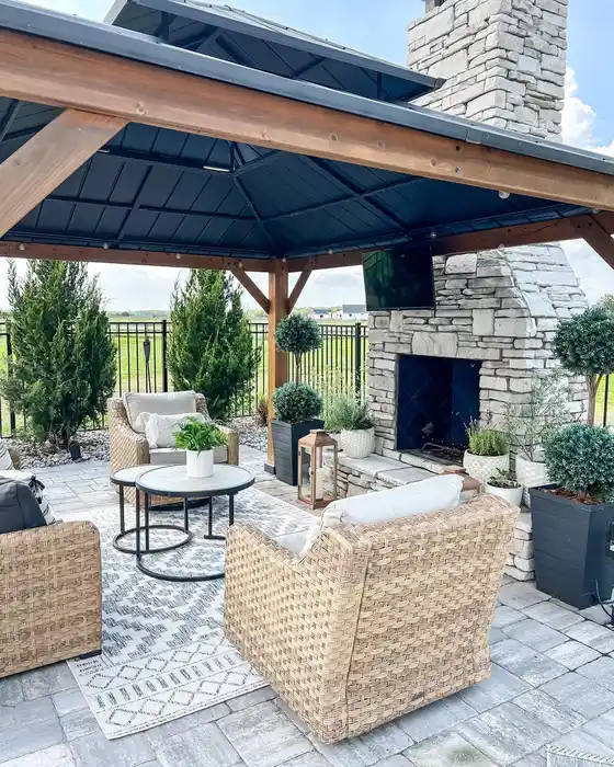 Pale outdoor rug beneath wicker-style furniture on a covered patio with a dark canopy.