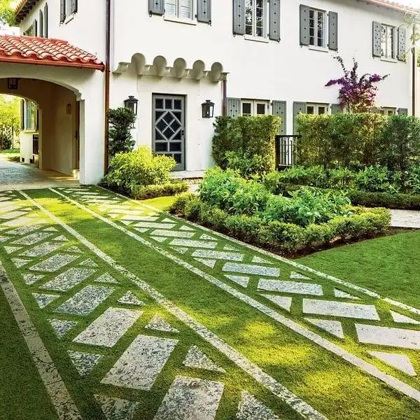 Pale driveway pavers separated by strips of green grass in a checkerboard pattern