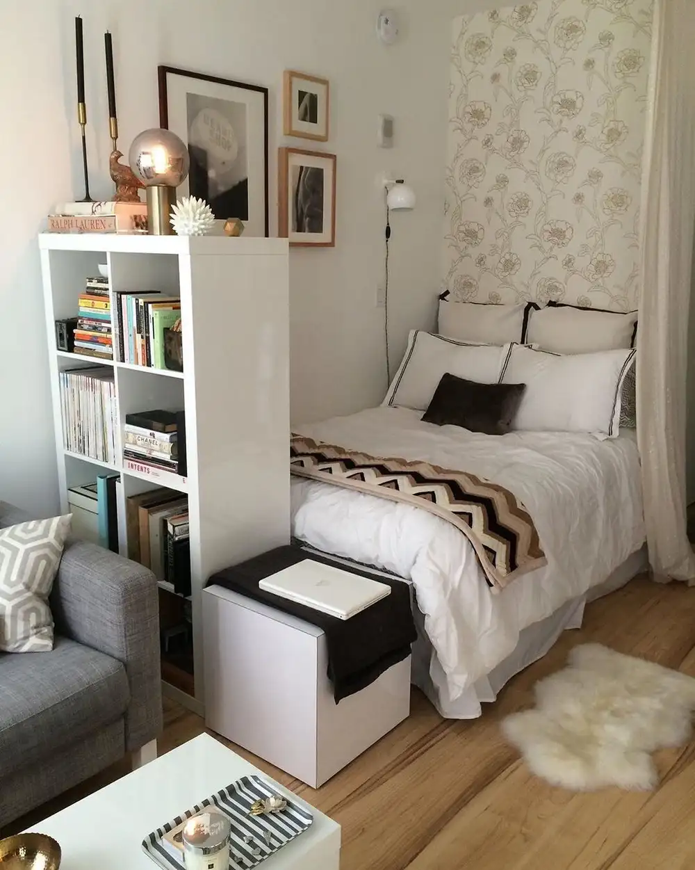 Small bedroom with open white shelving used as a room divider beside the bed