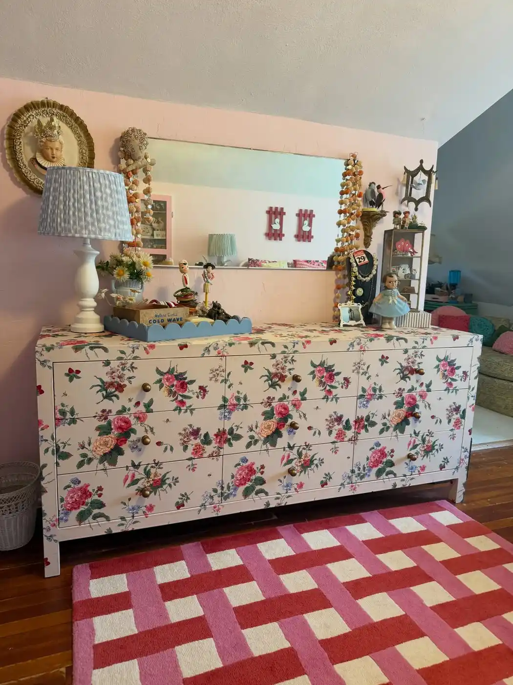 Colorful floral dresser styled with playful lamp, small decorative objects, and bold geometric rug
