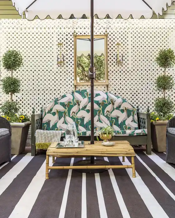 Bold striped outdoor rug beneath symmetrical patio seating with patterned cushions and greenery.