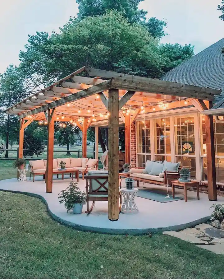 Spacious patio with large wooden pergola, multiple outdoor seating areas, and warm string lights