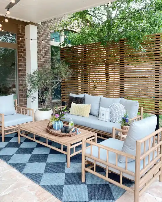 Blue and white checkerboard outdoor rug beneath pale outdoor seating and warm wooden furniture.