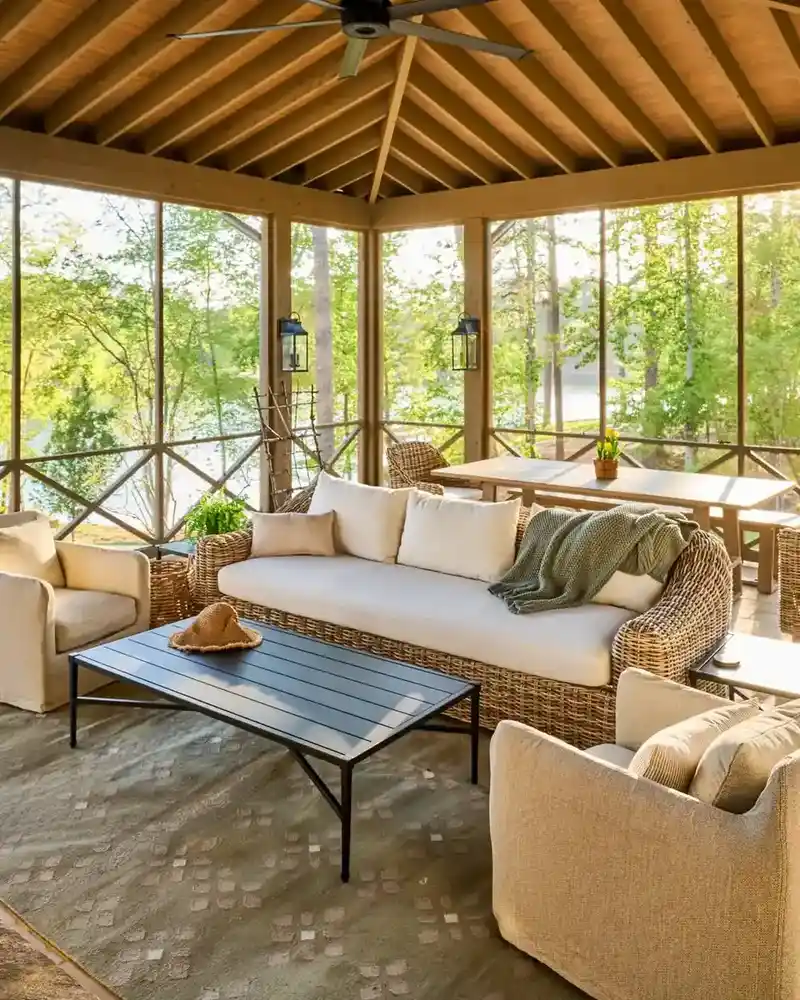 Large screened porch with wood ceiling, pale sofa and chairs, coffee table, and an open outdoor view.