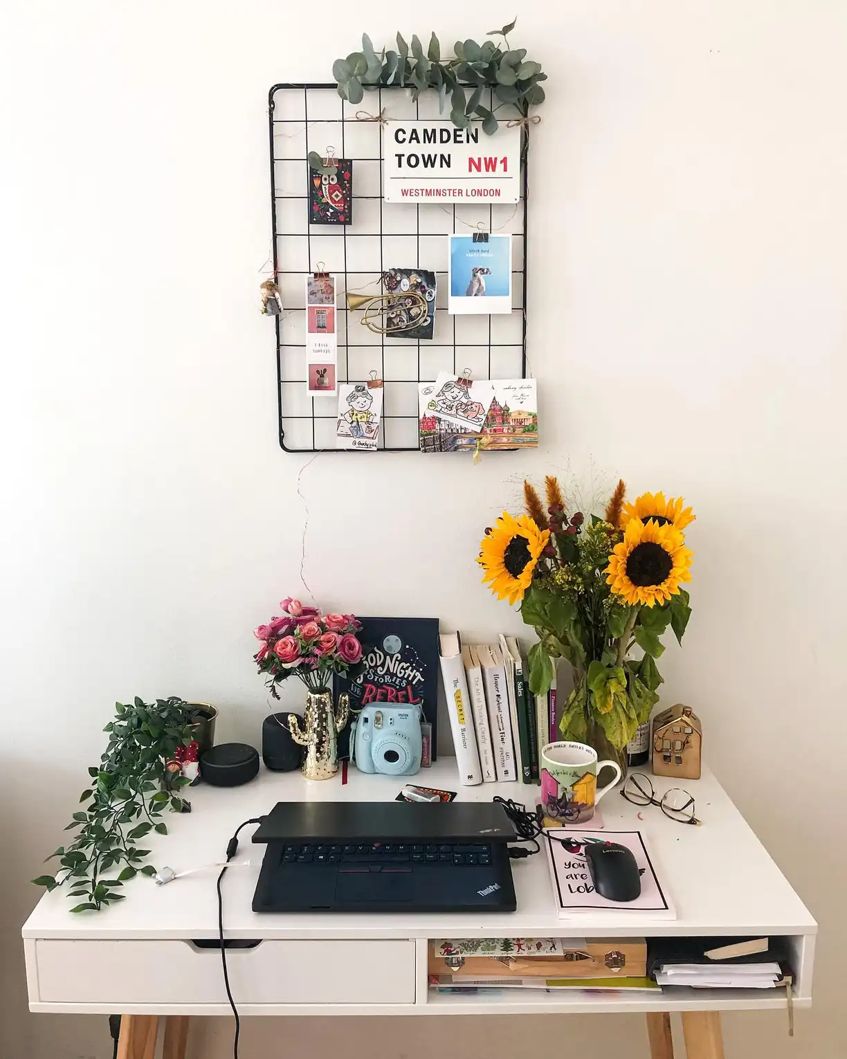 Dorm desk with sunflowers, wire memo grid, trailing plant, keyboard, and small accessories