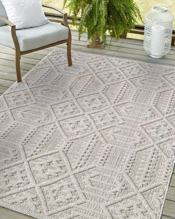 Pale beige outdoor rug with a subtle textured pattern beneath white patio seating.